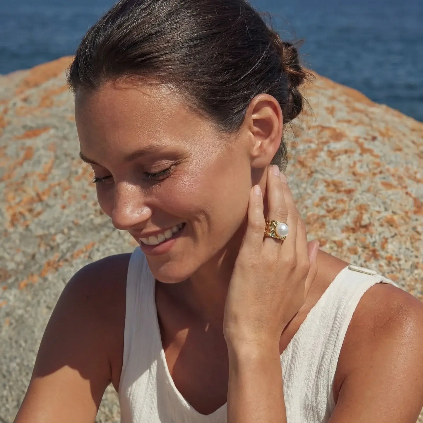 Golden Tide Pearl Ring | Freshwater Gold Ring – Glitter By Kate Wild showcased on a smiling model by the seaside.