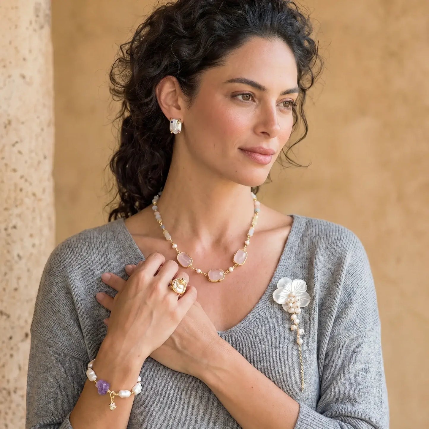 Woman showcasing floral pearl brooch on gray top - romantic jewelry style